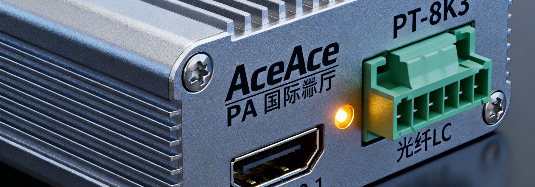 PA国际厅PlayAce第三代光纤传输器PT-8K3产品特写，金属外壳带有散热鳍片，接口面板展示HDMI 2.1和光纤LC接口，LED状态指示灯发出琥珀色光芒。